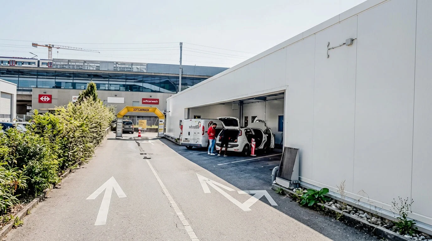 Due persone caricano oggetti in auto davanti a un edificio bianco vicino a un ingresso con frecce dipinte. Due persone caricano oggetti in auto davanti a un edificio bianco vicino a un ingresso con frecce dipinte.