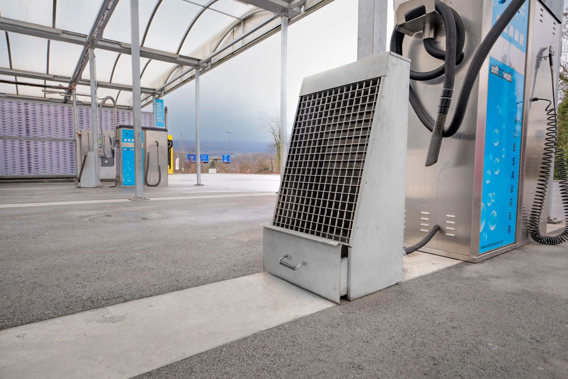 Stazione di ricarica per veicoli elettrici in Svizzera con caricatori blu e un pulitore per tappetini.